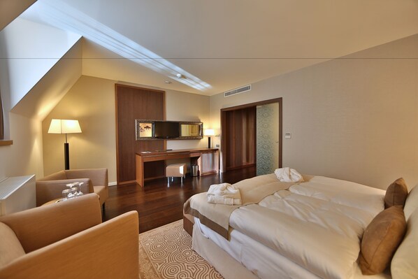 A hotel room with a bed, a desk, a chair, and a TV.