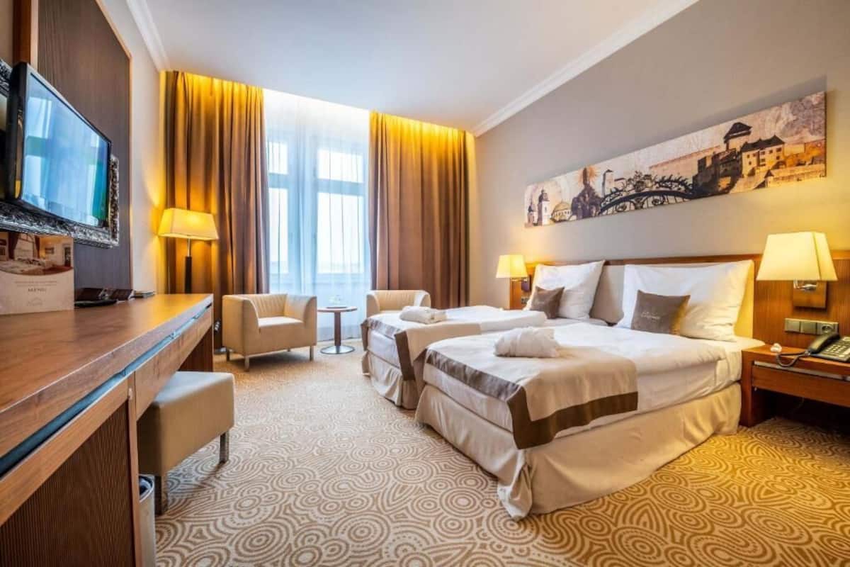 Una habitación de hotel con dos camas, un escritorio, una silla y un televisor.