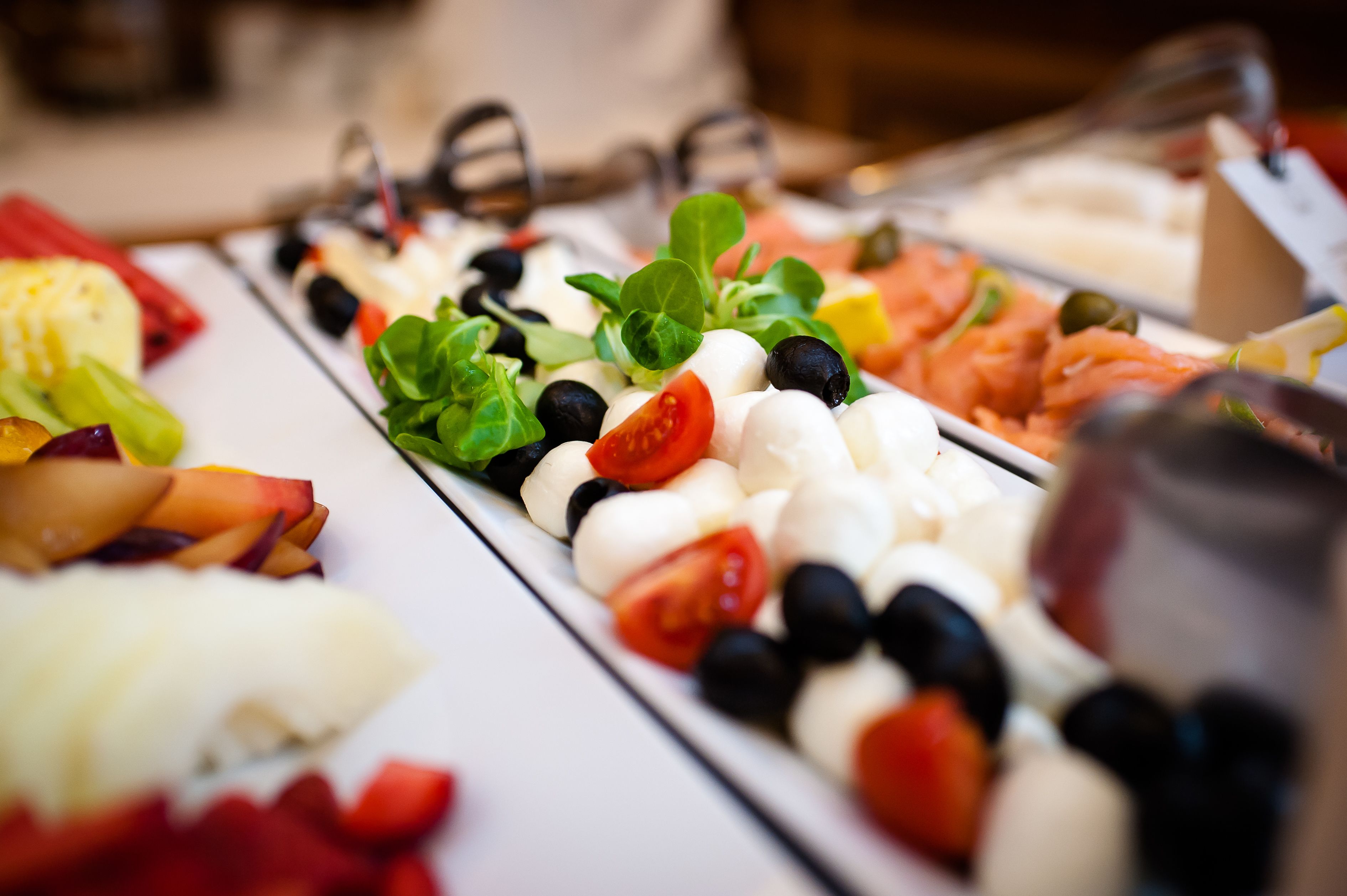 Un bufé con diferentes opciones de comida, como tomates, aceitunas, mozzarella y salmón.