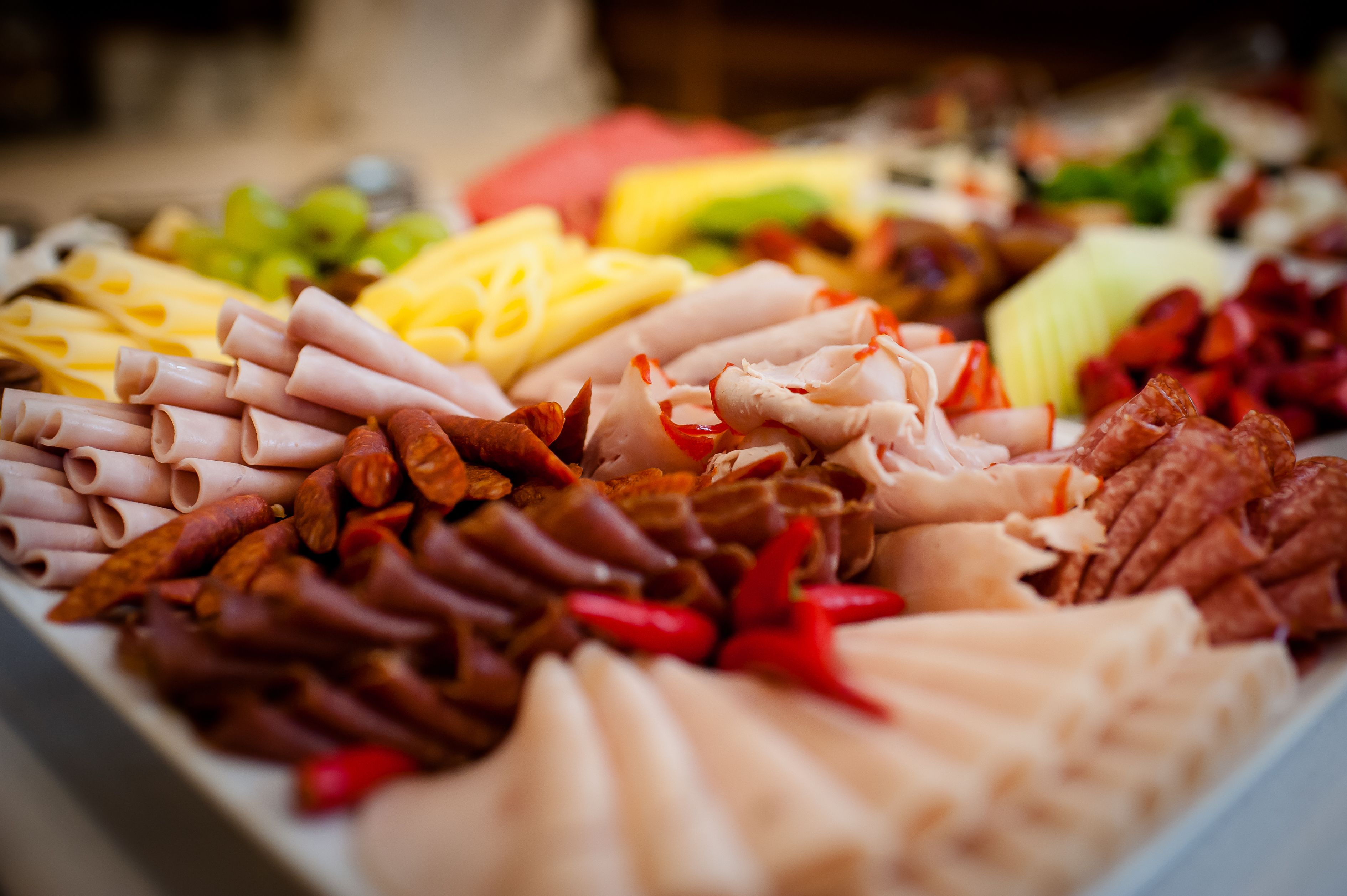 A charcuterie board with various meats, cheeses, and fruits.