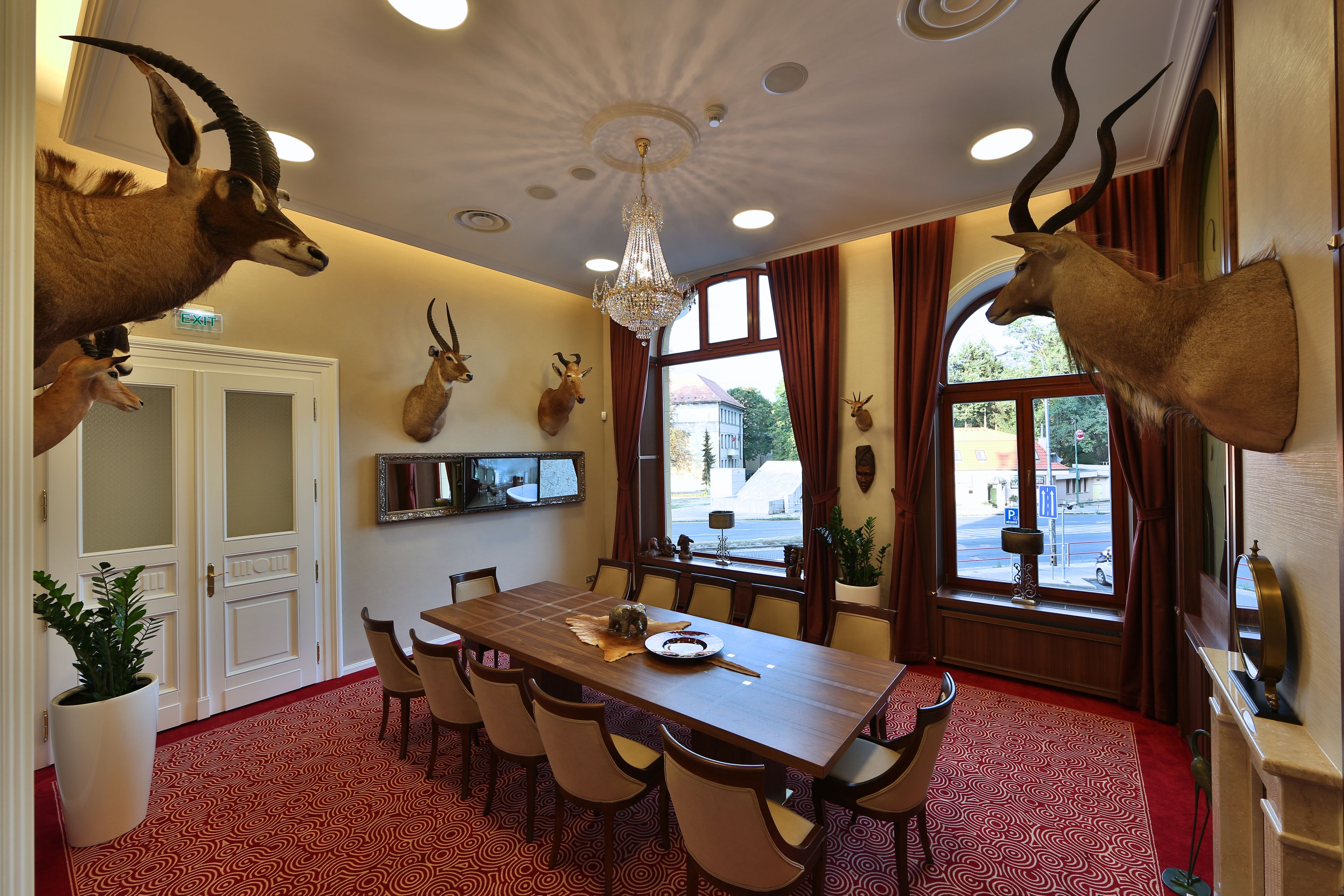A dining area with a chandelier, mounted animal heads, a large table, and chairs.