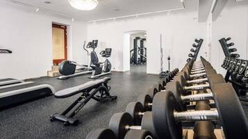 A gym with treadmills, elliptical machines, and a bench press.