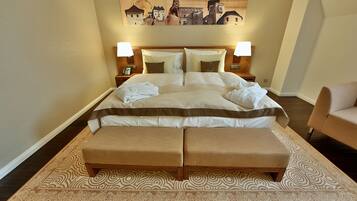 Una cama bien hecha con un almohadón grande, una mesita de noche con una lámpara y una silla a un lado.