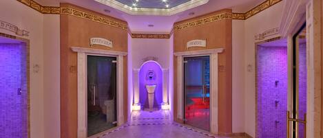 A hotel corridor with a central atrium, a tiled floor, and a ceiling with star-like lights.
