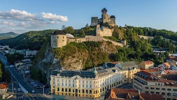 Um castelo histórico numa colina com vista para uma cidade, com um edifício notável em primeiro plano.