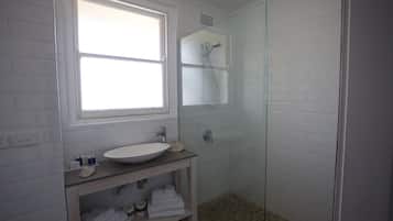 A bathroom with a white sink, a glass shower enclosure, and a window providing natural light.