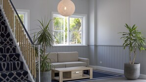 A staircase with a geometric pattern, a beige sofa, a wooden coffee table, and two potted plants. - Seabreeze Hotel (Nelson Bay)
