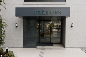 Entrada de hotel con diseño moderno, con puerta de cristal y un letrero que dice 'SOTETSU FRESAINN'.