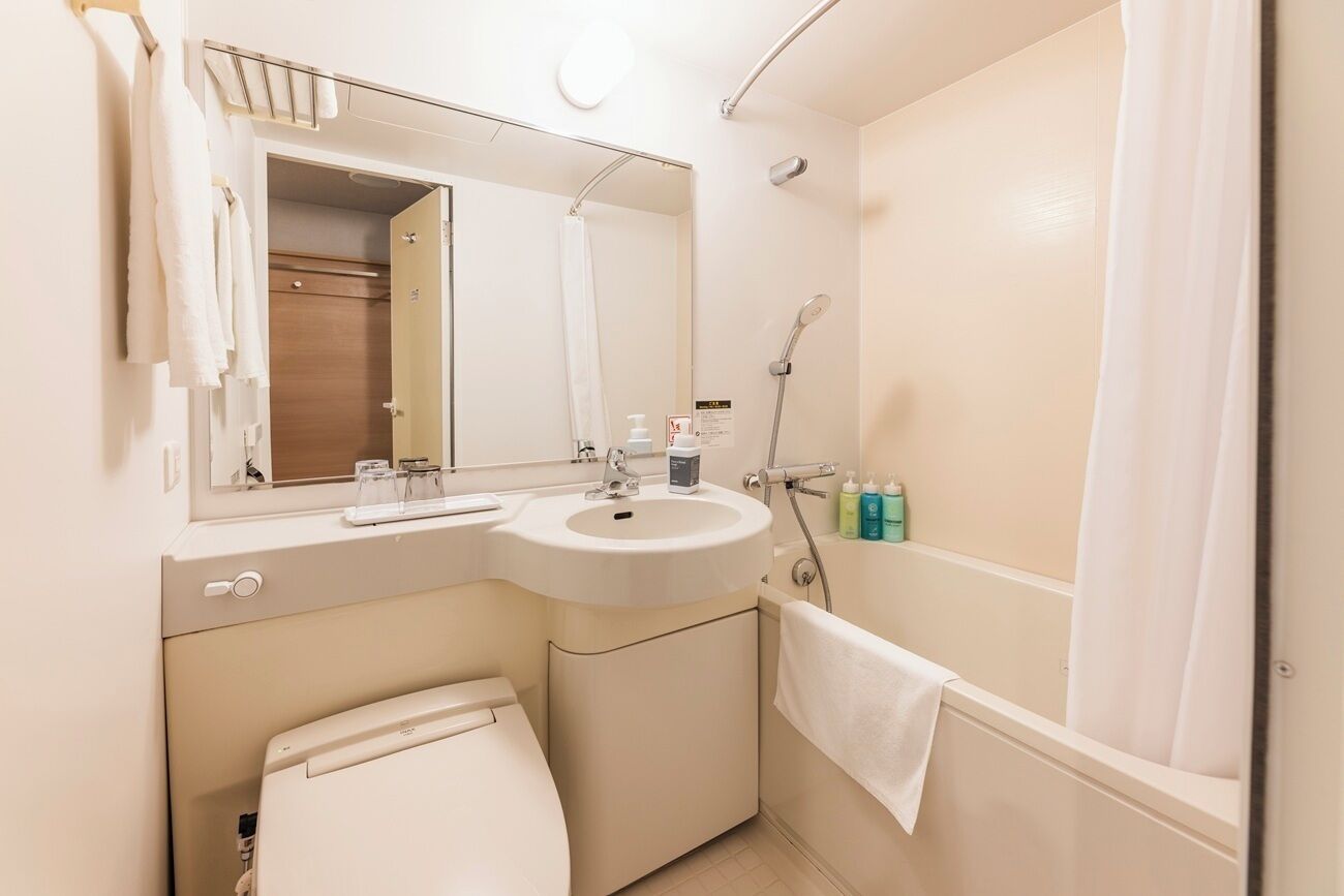 A bathroom with a sink, mirror, towel rack, and shower.