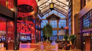 A spacious lobby with a high ceiling, large windows, and a central plant area.