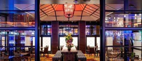 The exterior of Red Lotus Asian Kitchen with a neon sign, a flower motif, and a wooden floor.