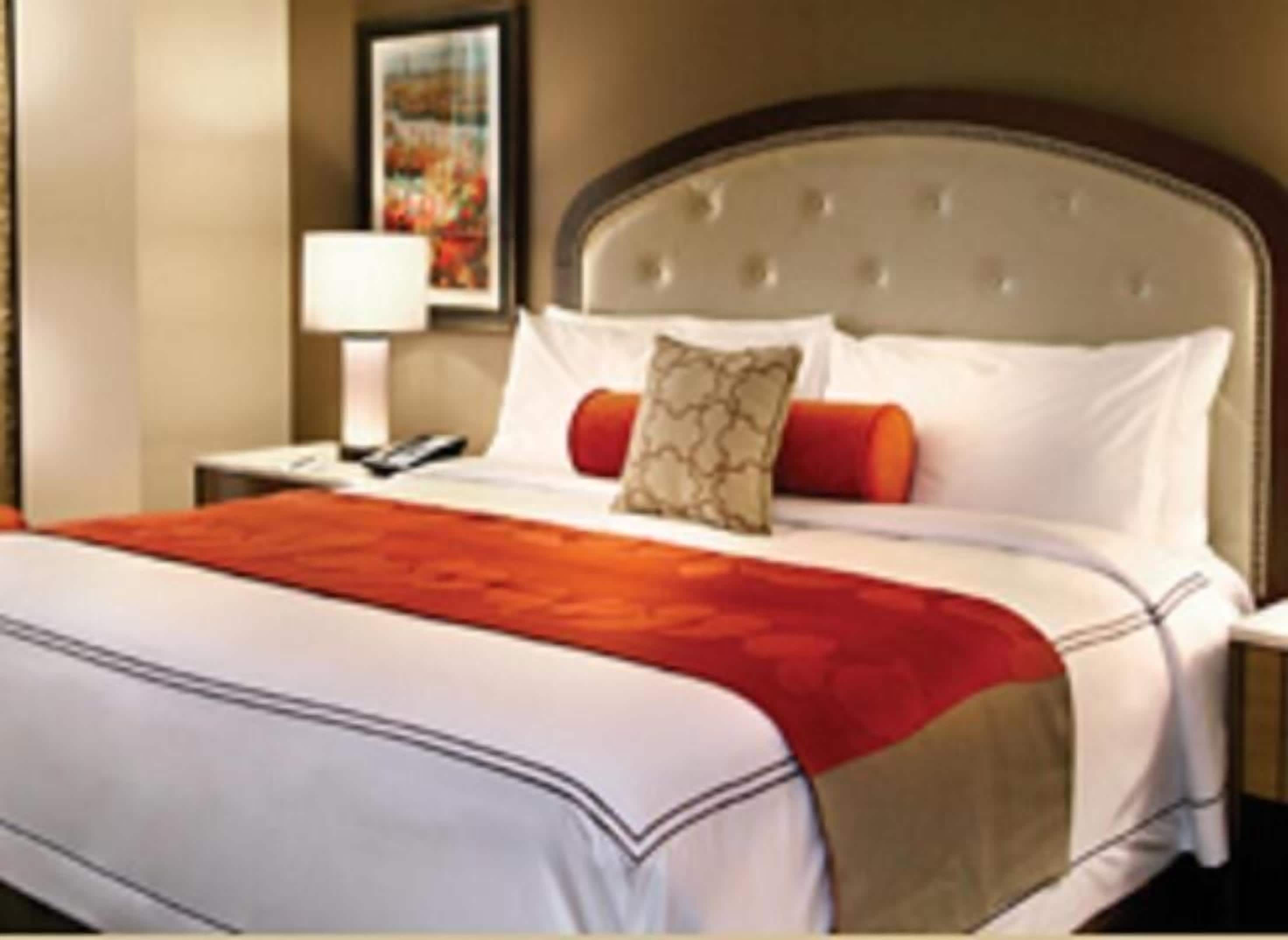 Una habitación de hotel con una cama grande, una mesita de noche, una lámpara y un cuadro en la pared.