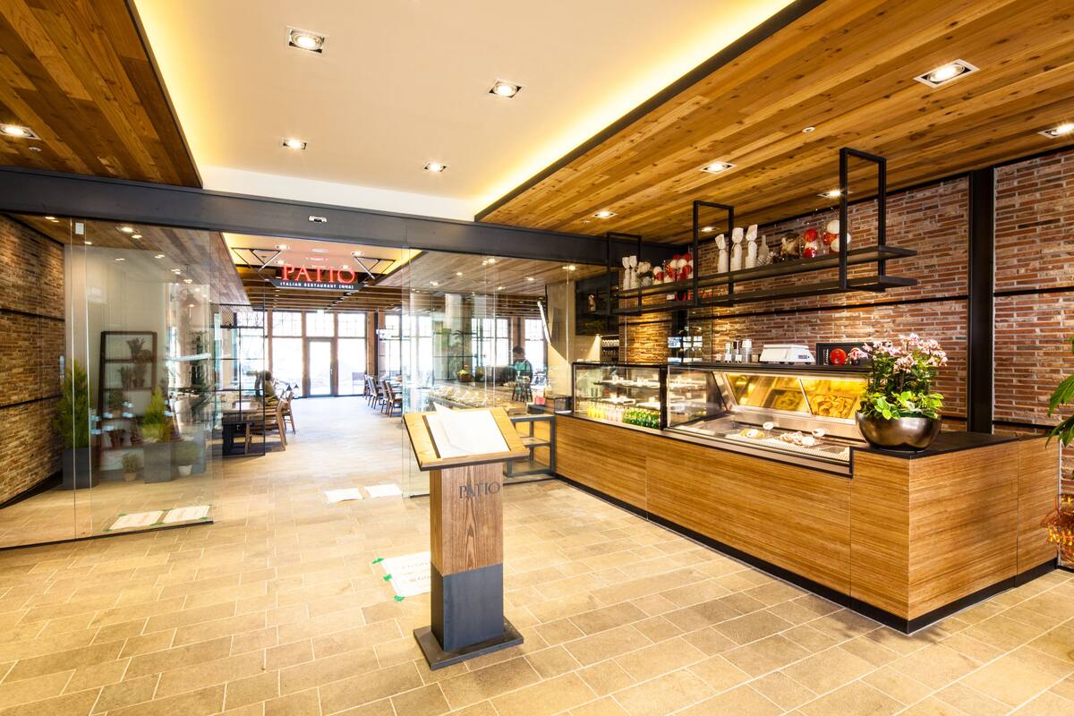 A modern interior with a wooden reception desk, a glass display case, and a brick wall.