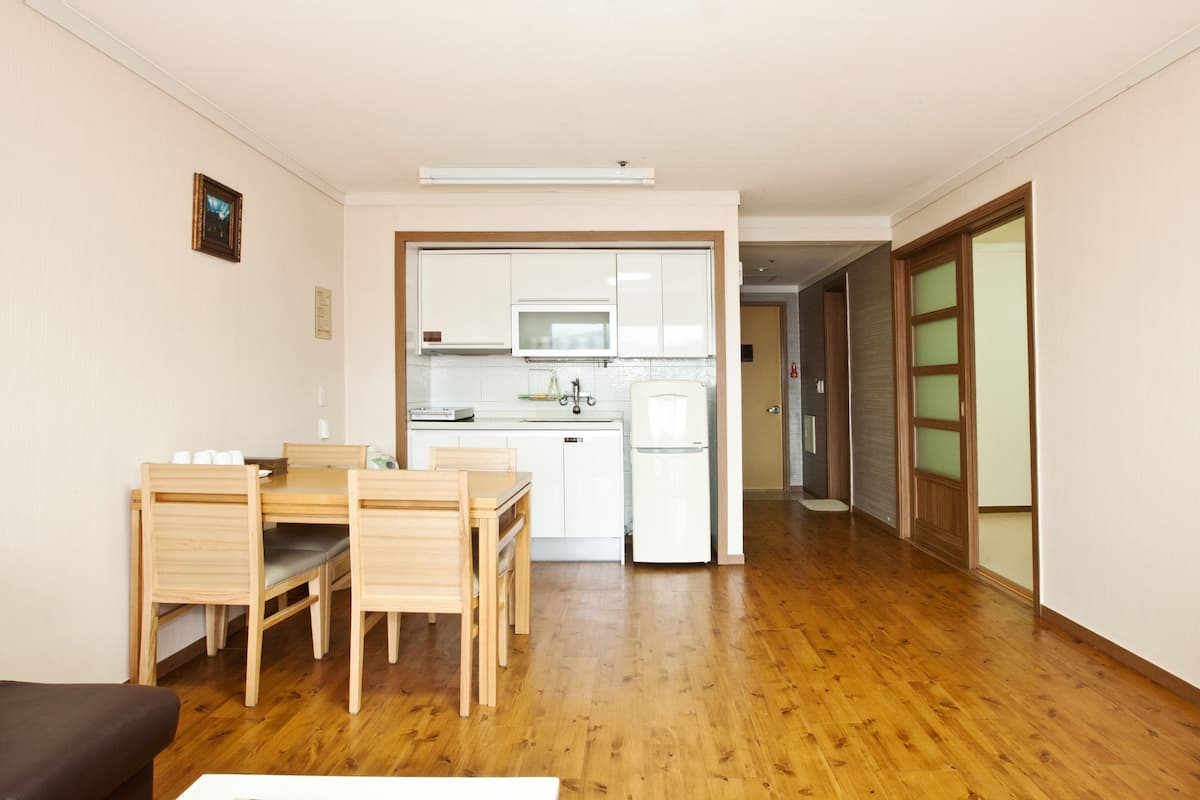 A compact living space with a kitchenette, wooden flooring, and a dining area.