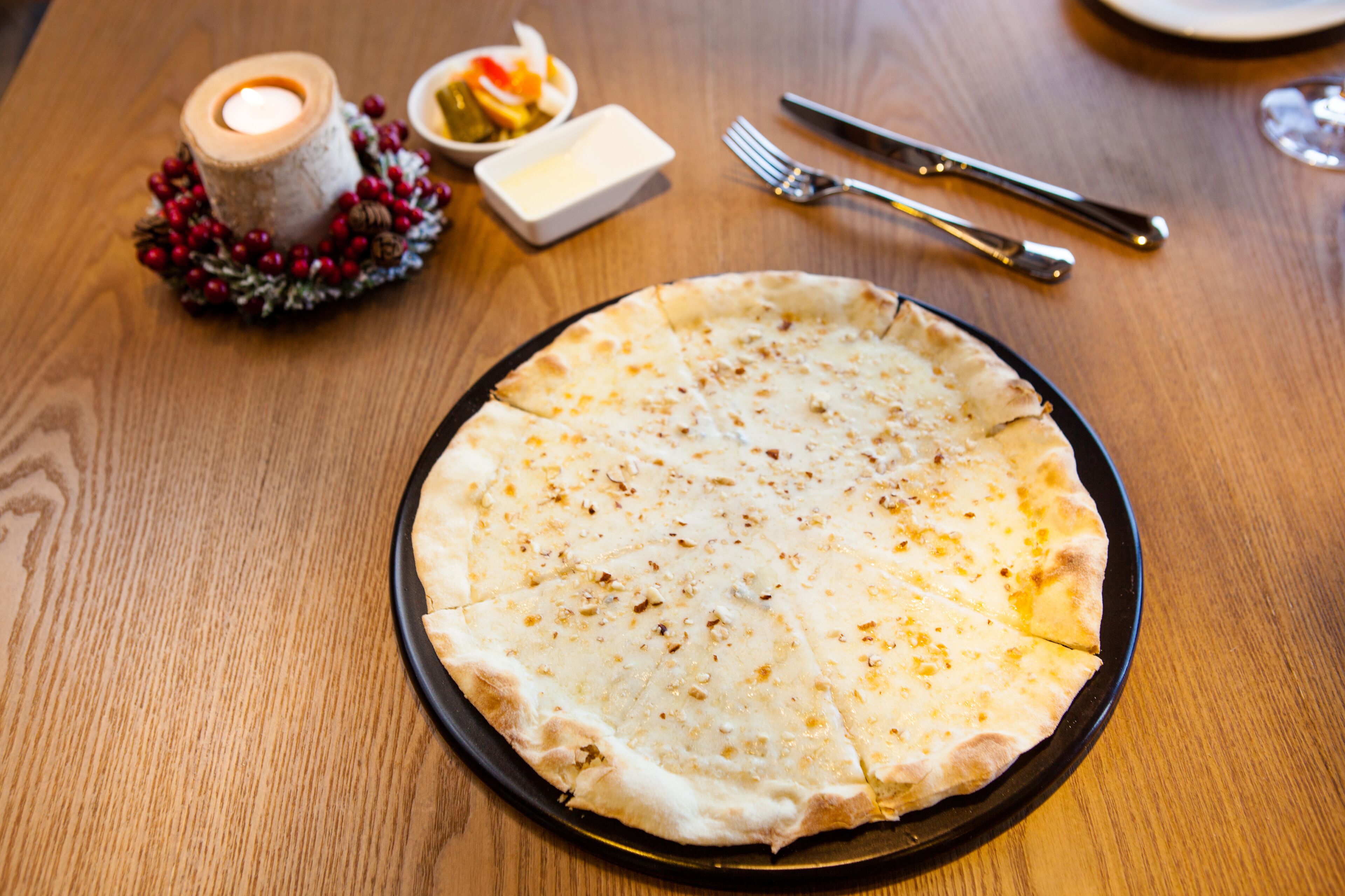 Un plato negro redondo con un pan plano sobre una mesa de madera.