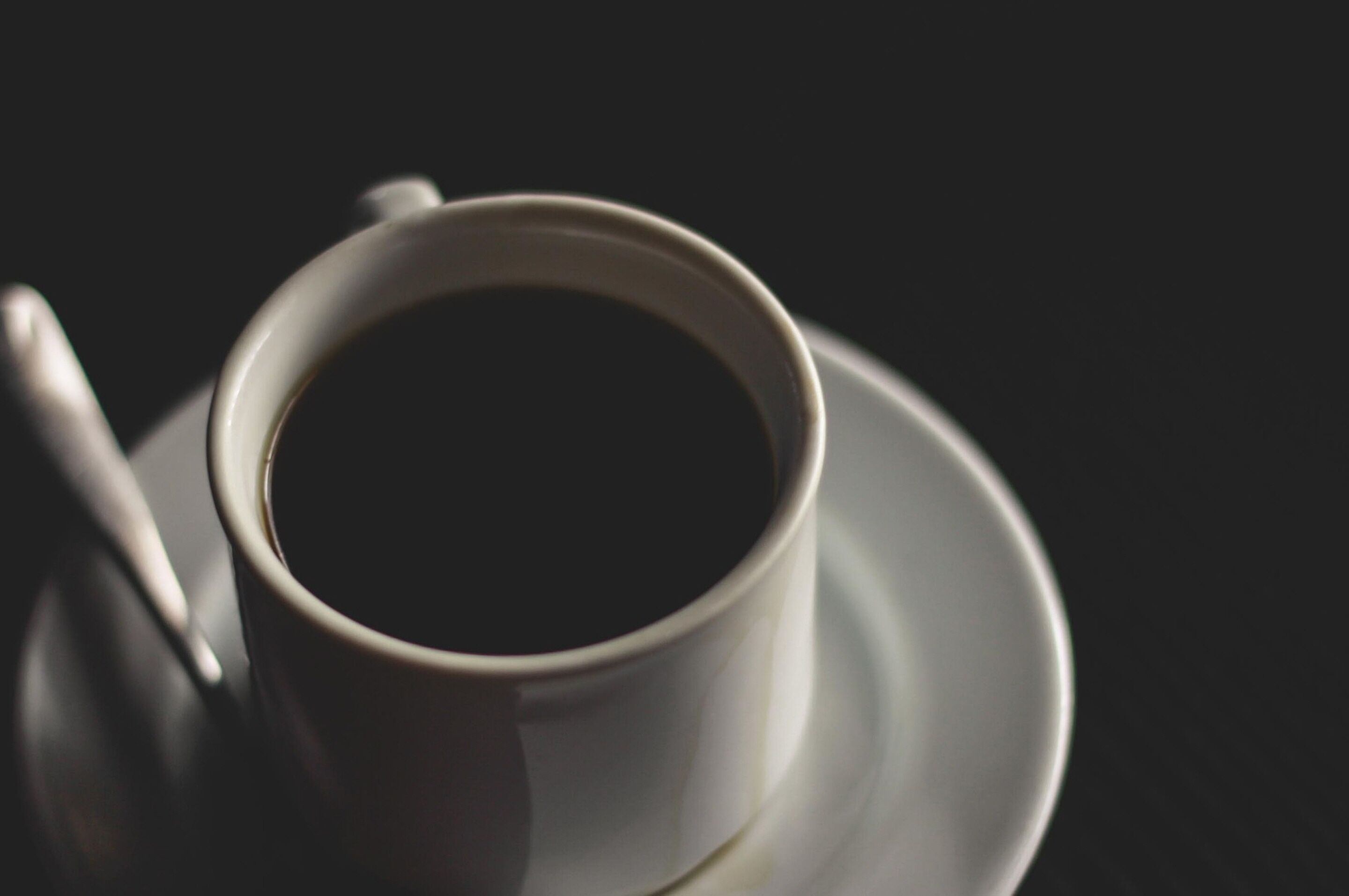 Una taza de café negro sobre un plato.