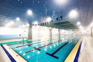 An indoor swimming pool with clear lanes, a tiled floor, and a ceiling with lights.
