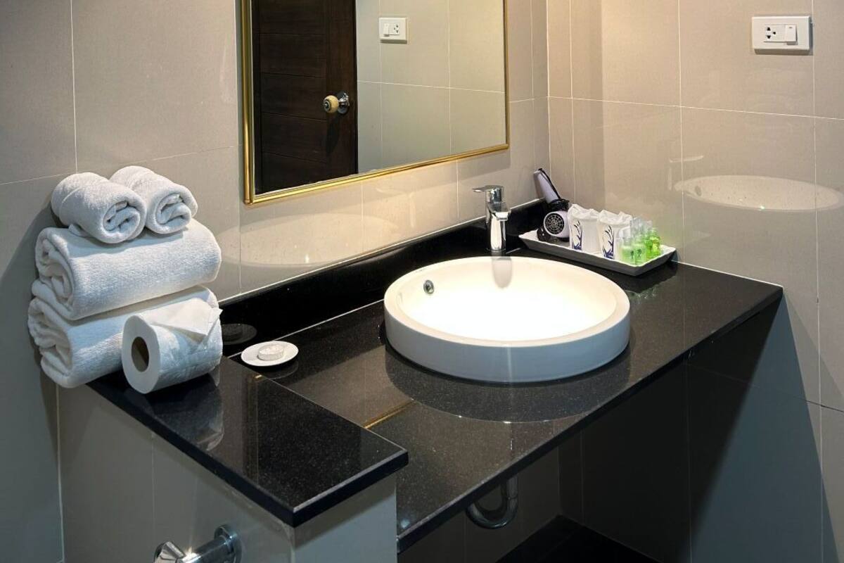 A modern bathroom with a large mirror, a round sink, and neatly folded towels.