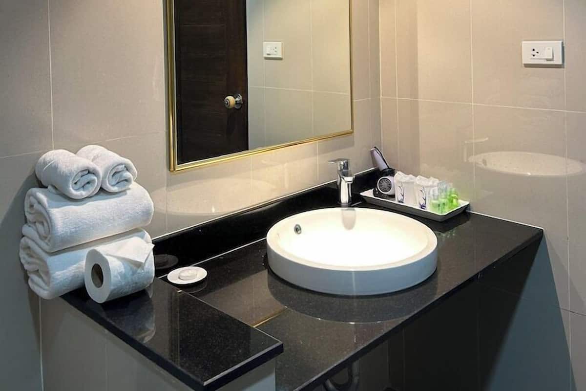 A modern bathroom with a large mirror, a round sink, and neatly folded towels.