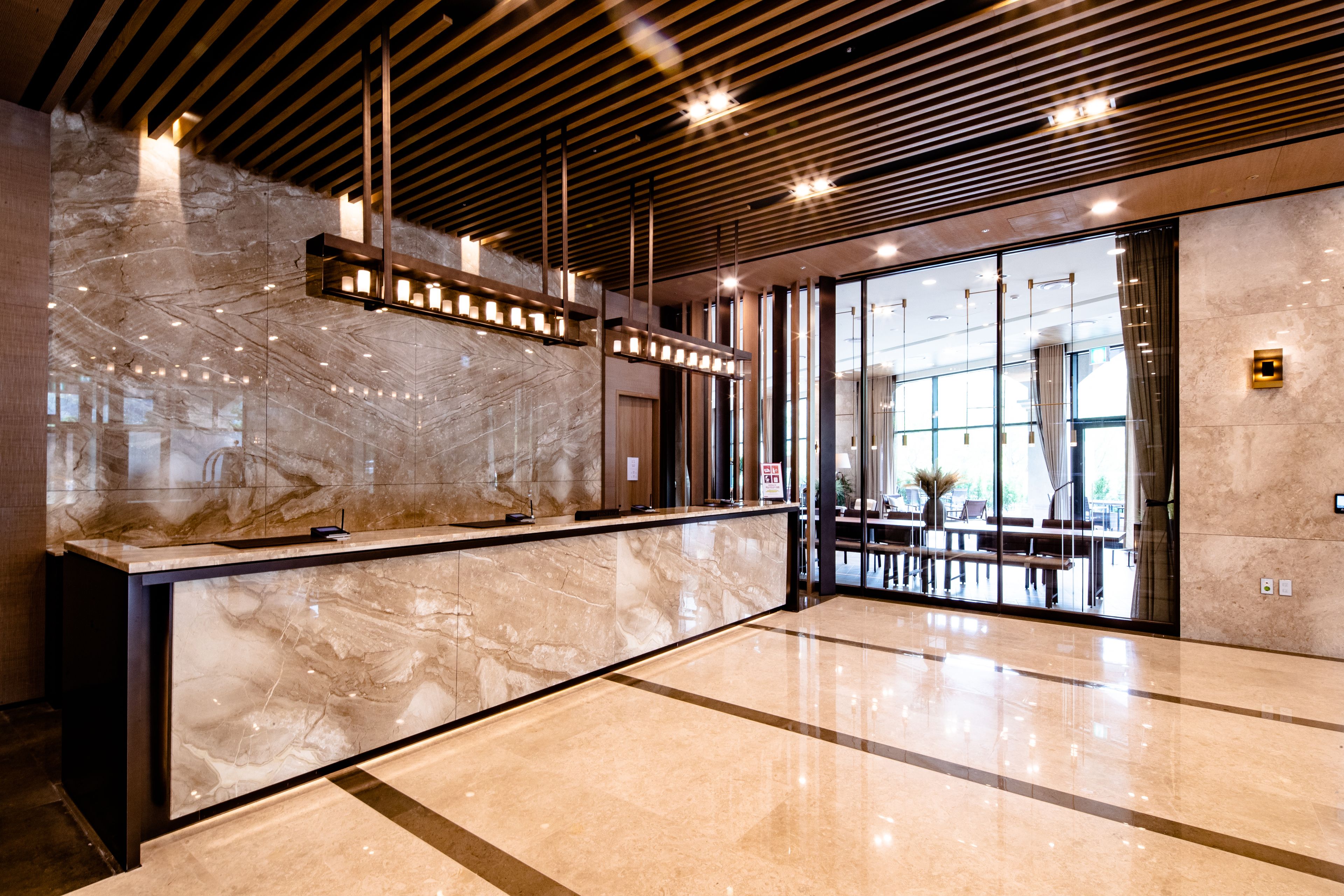 A modern reception area with a marble counter, wooden ceiling beams, and large windows.