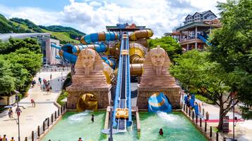A water park with a large slide, two large sphinx statues, and a pool area.