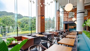 A restaurant with large windows, wooden tables, and cushioned seating.