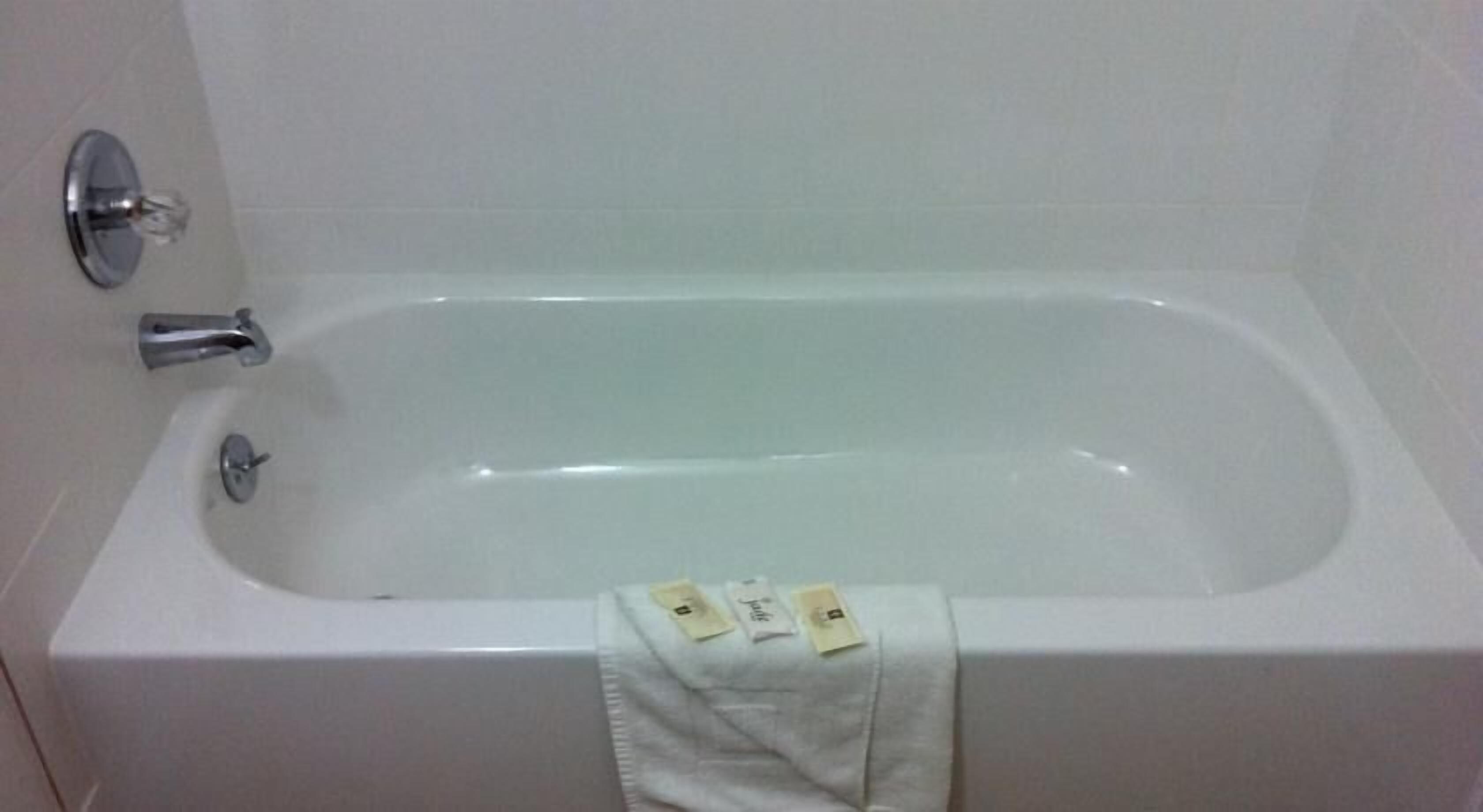 Eine weiße Standardbadewanne mit Wasserhahn und Handbrause.