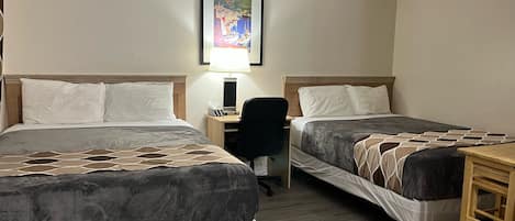 Habitación de hotel con dos camas, un escritorio, una silla y un cuadro en la pared.
