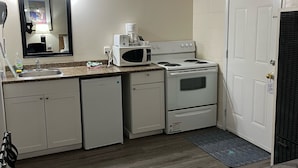 Una kitchenette compacta equipada con microondas, estufa y lavavajillas.