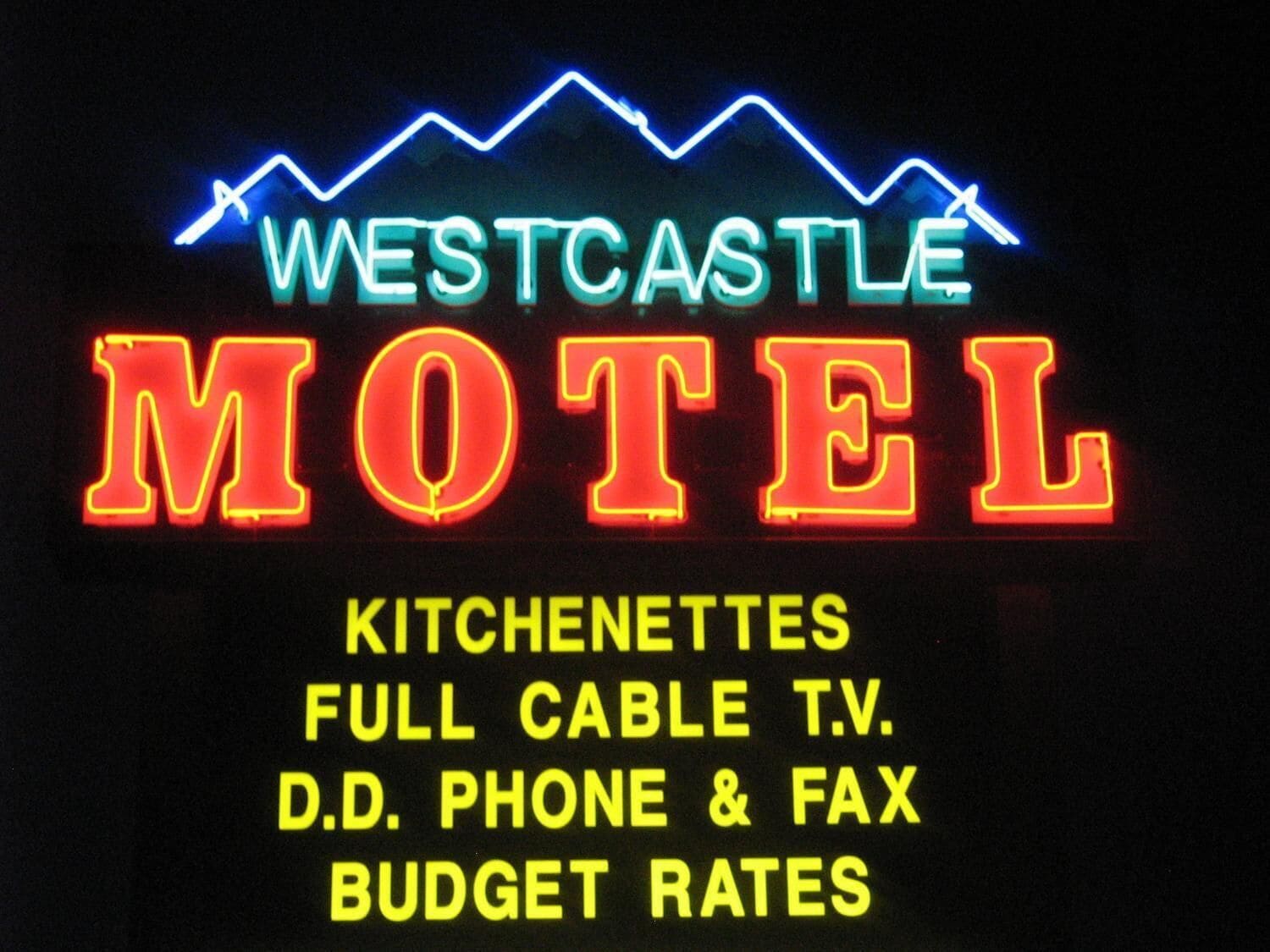 A neon sign for the Westcastle Motel advertising amenities like kitchenettes, full cable TV, and D.D. phone & fax.