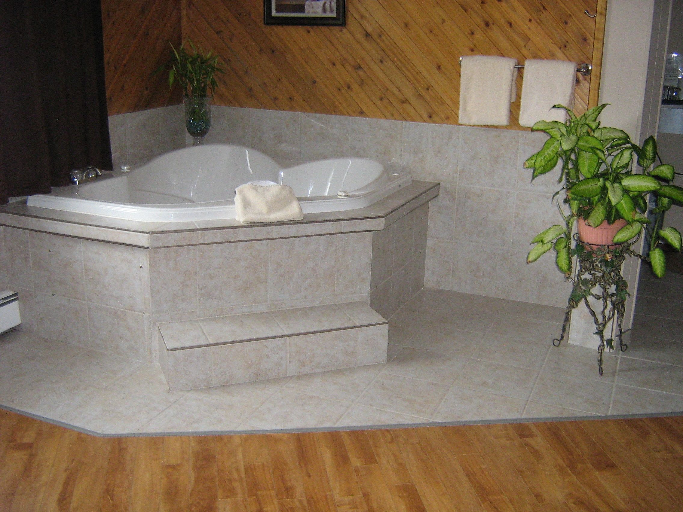 A bathroom with a bathtub, a potted plant, and a towel rack.