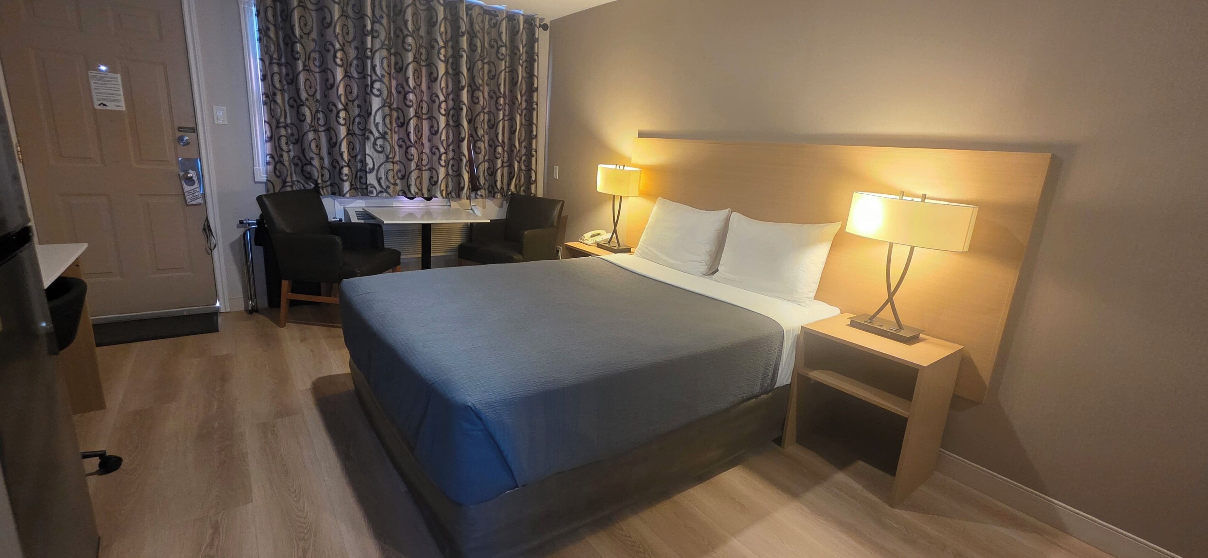 Una habitación de hotel con cama, lámparas de noche, escritorio y una silla.