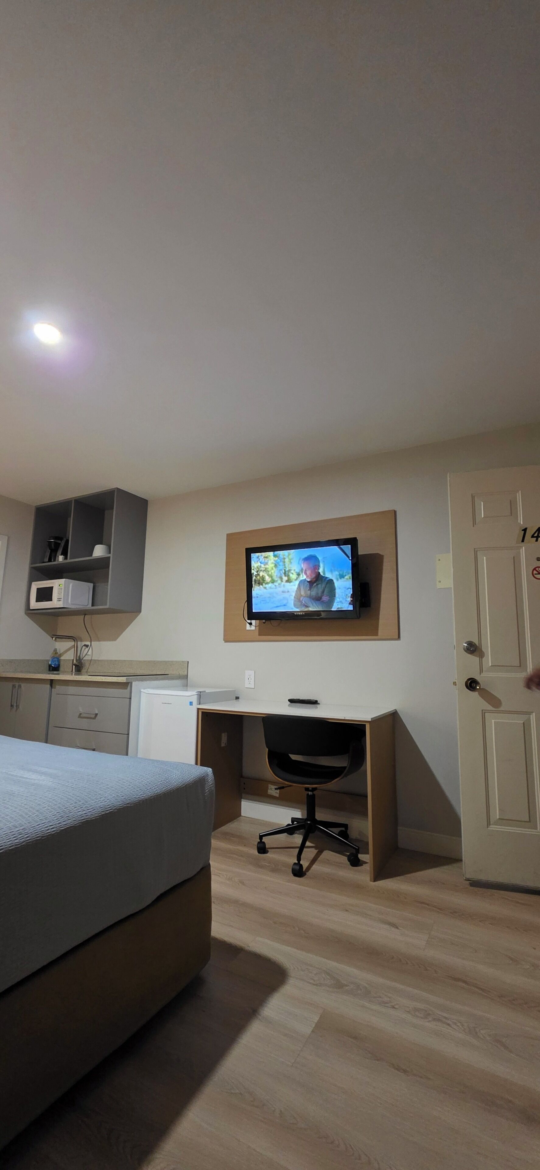 Un dormitorio con una cama, un escritorio, un televisor y un microondas.