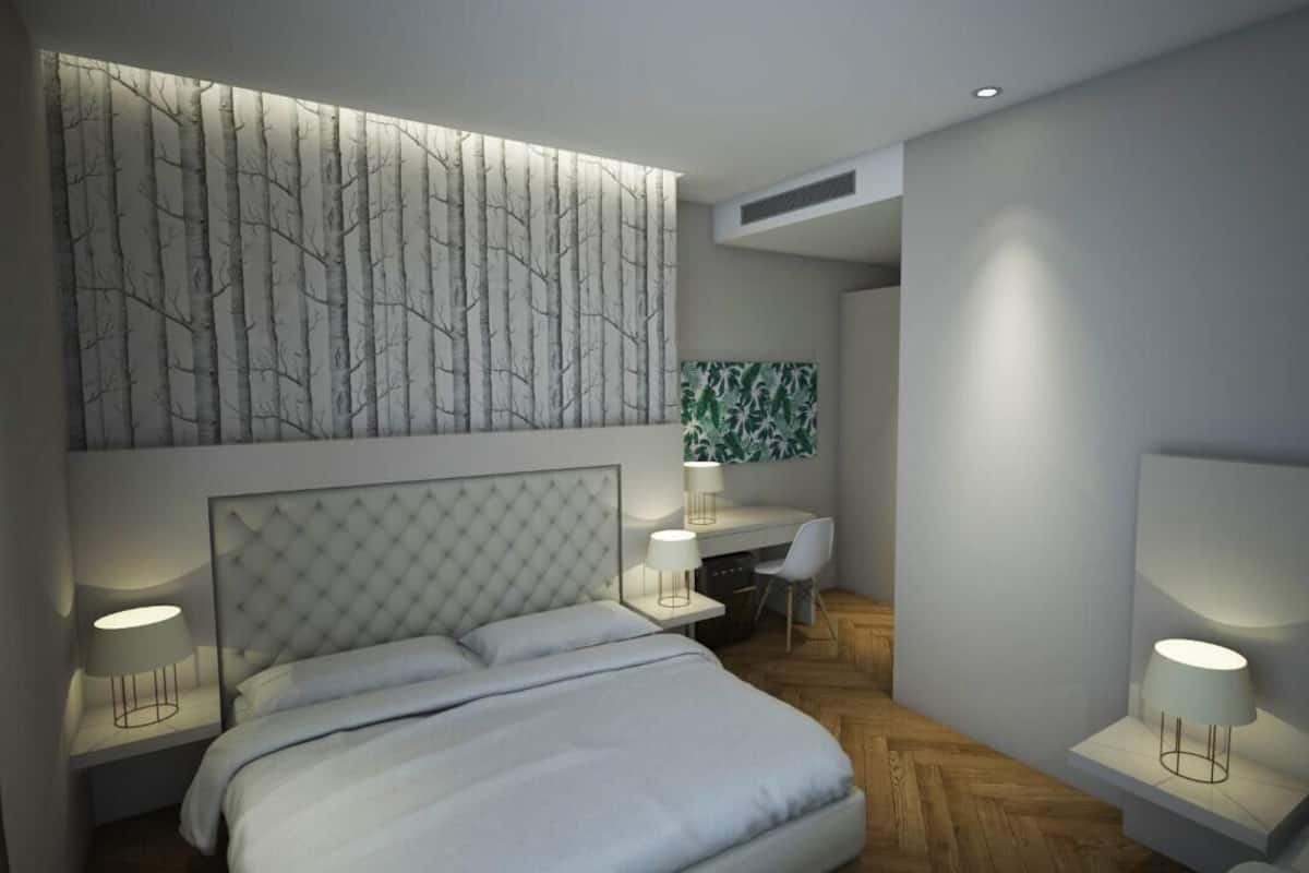 Ein modernes Schlafzimmer mit einem großen Bett, Nachttischen, einem Schreibtisch und einem Sessel.