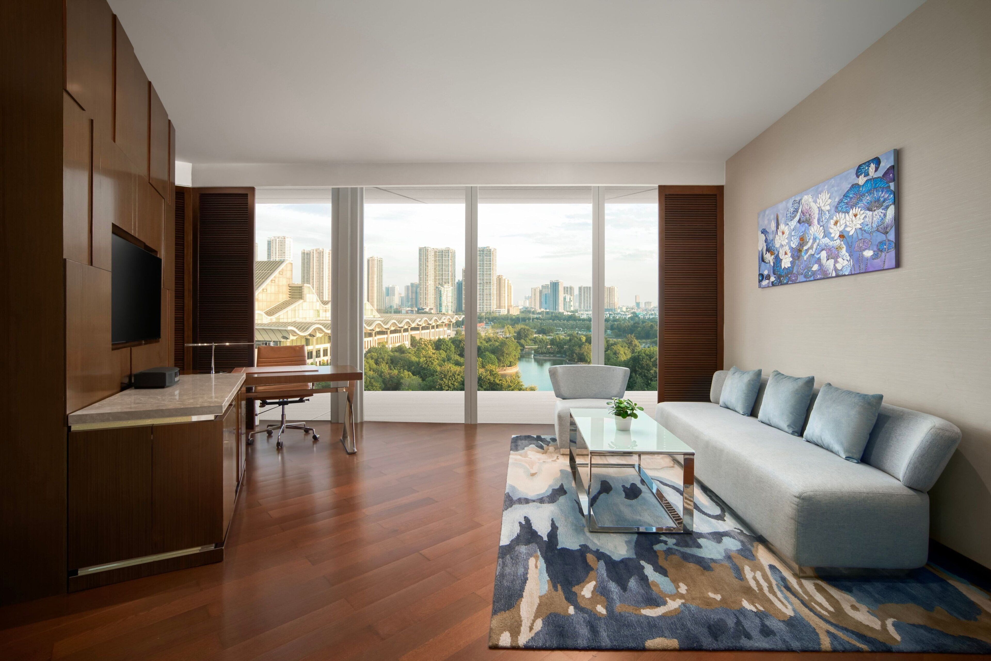 Una sala de estar moderna con un ventanal grande, un sofá, una mesa de centro y un televisor sobre un mueble de madera.