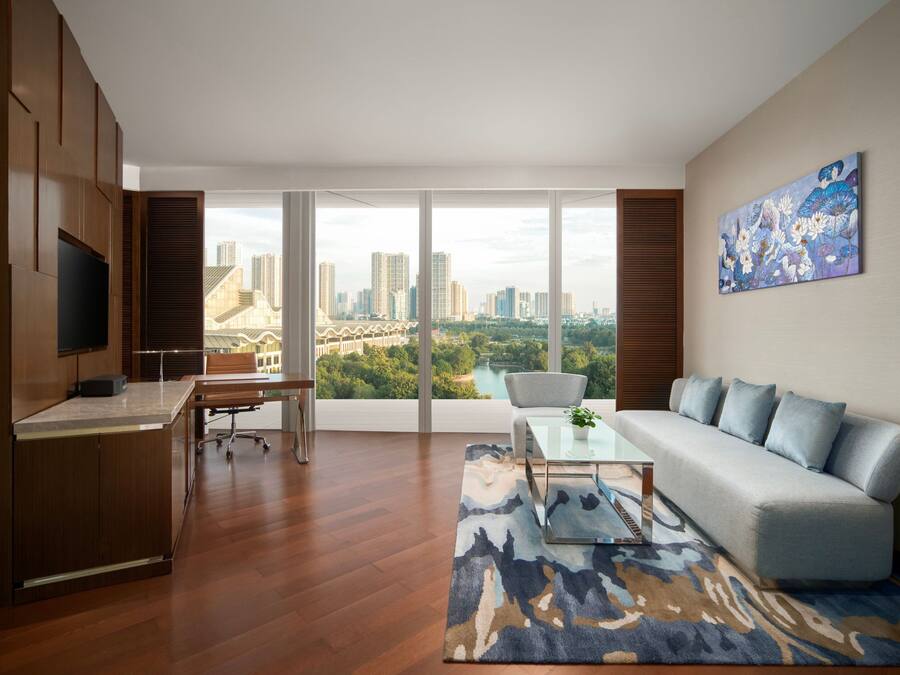 Una sala de estar moderna con un ventanal grande, un sofá, una mesa de centro y un televisor sobre un mueble de madera.