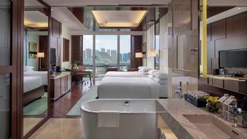 A modern hotel room with a large bathtub, two beds, a TV, and a city view.