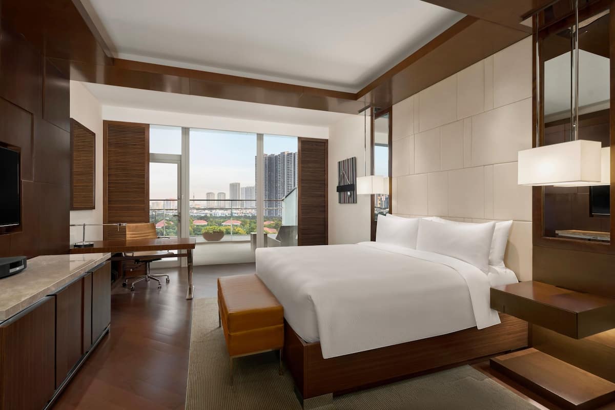 Quarto de hotel moderno com uma cama grande, uma escrivaninha e vista para a cidade.