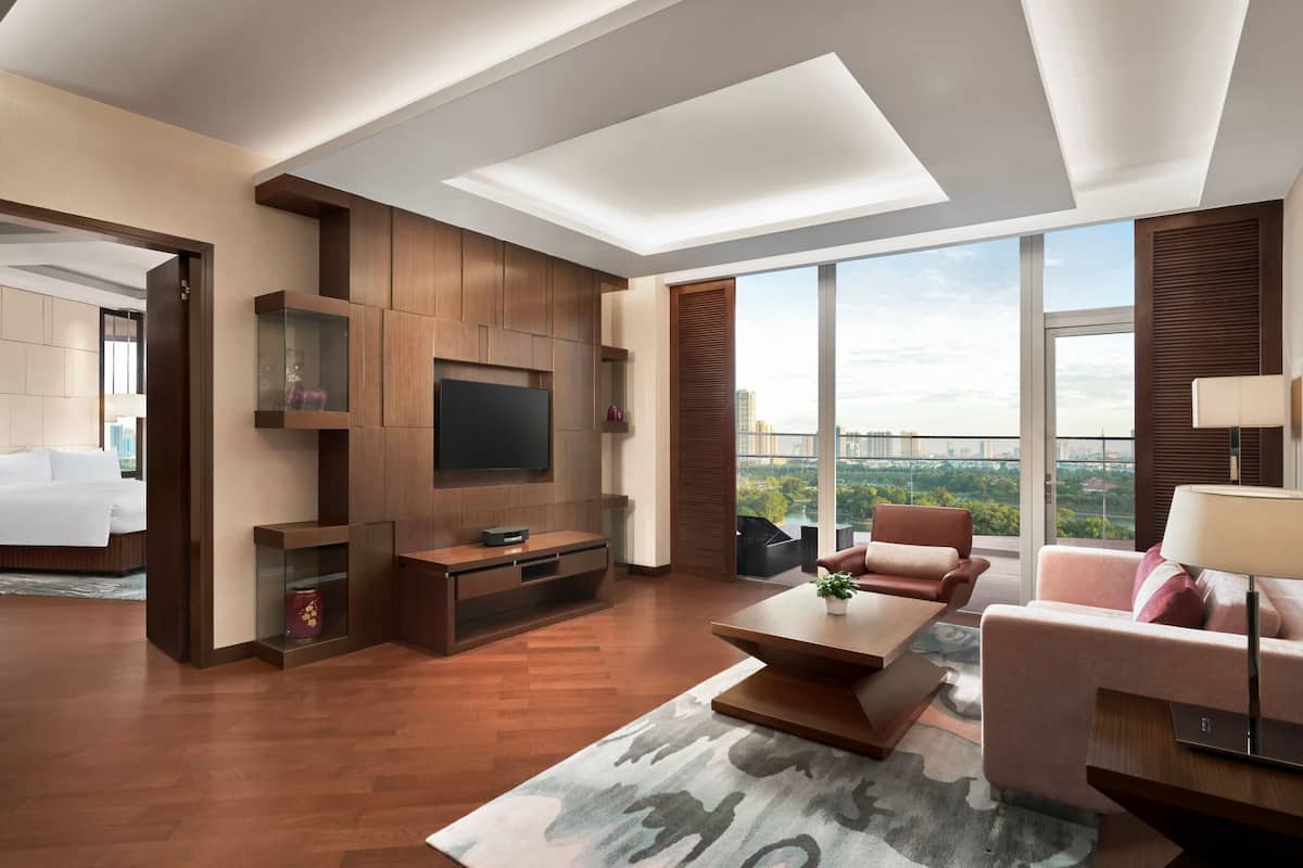 Uma sala de estar moderna com televisão de tela plana, móveis de madeira, uma janela grande com vista para a cidade e um espaço de estar aconchegante.