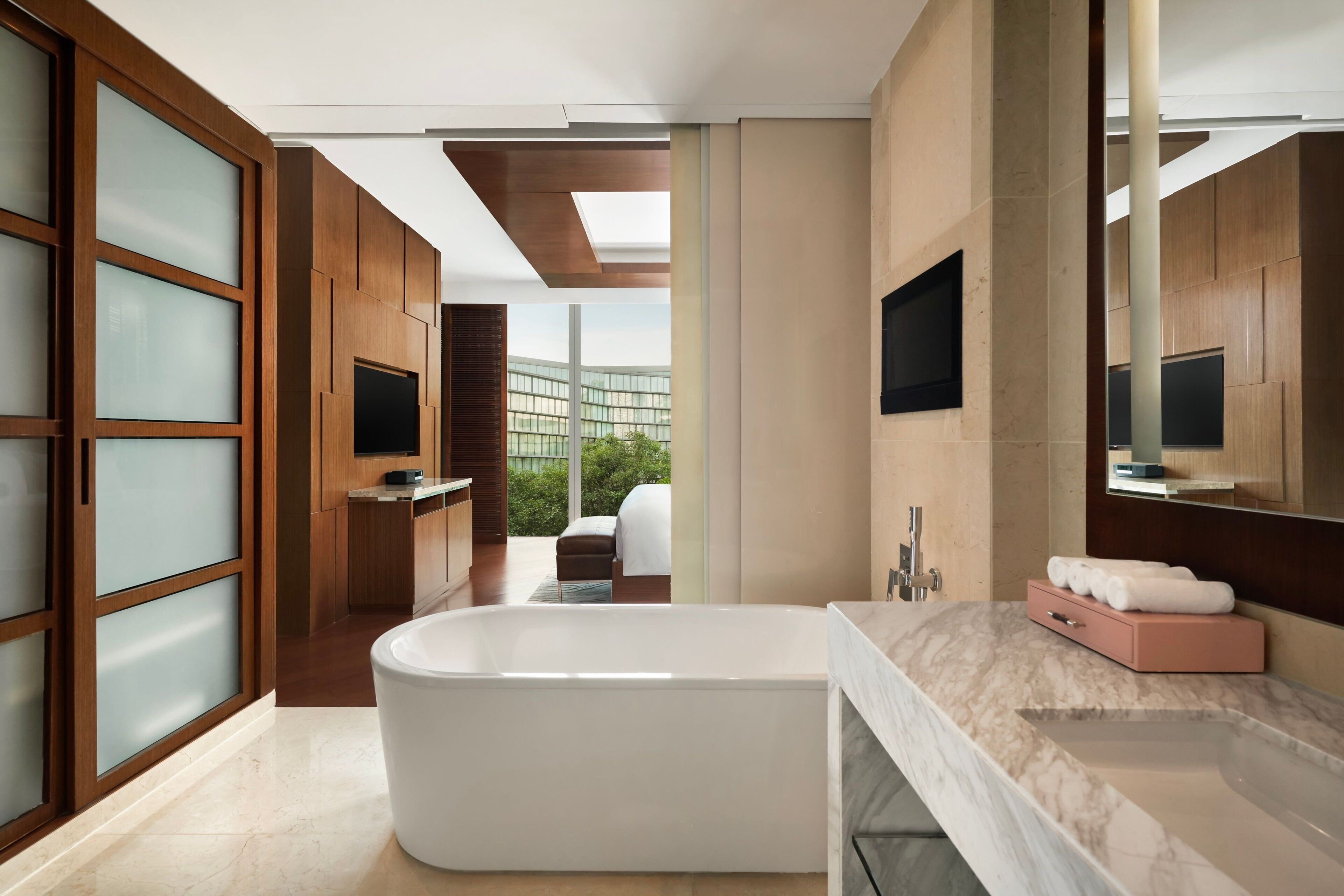 A modern bathroom with a freestanding bathtub, a marble countertop, and a large mirror.