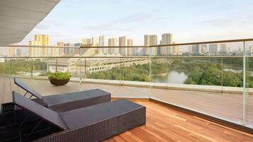 A balcony with wicker furniture, a view of a cityscape, and a river.