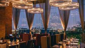 A restaurant with tables set for dining, large windows with curtains, and hanging light fixtures. - JW Marriott Hotel Hanoi (Hanoi)
