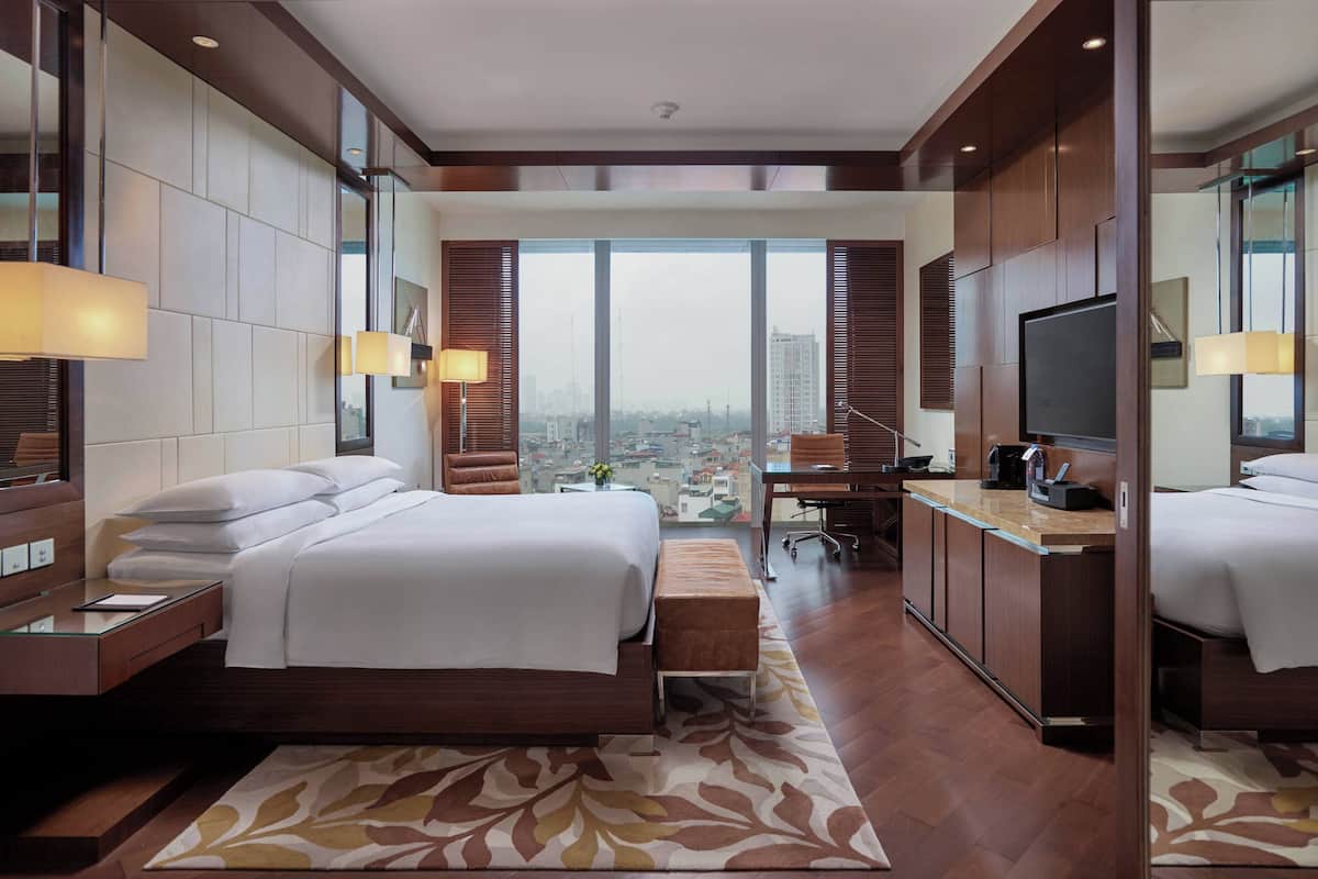 Quarto de hotel moderno com uma cama grande, uma escrivaninha e uma televisão.