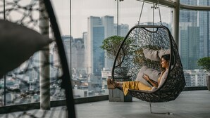 A person relaxing in a hanging chair with a cityscape view. - JW Marriott Hotel Hanoi (Hanoi)