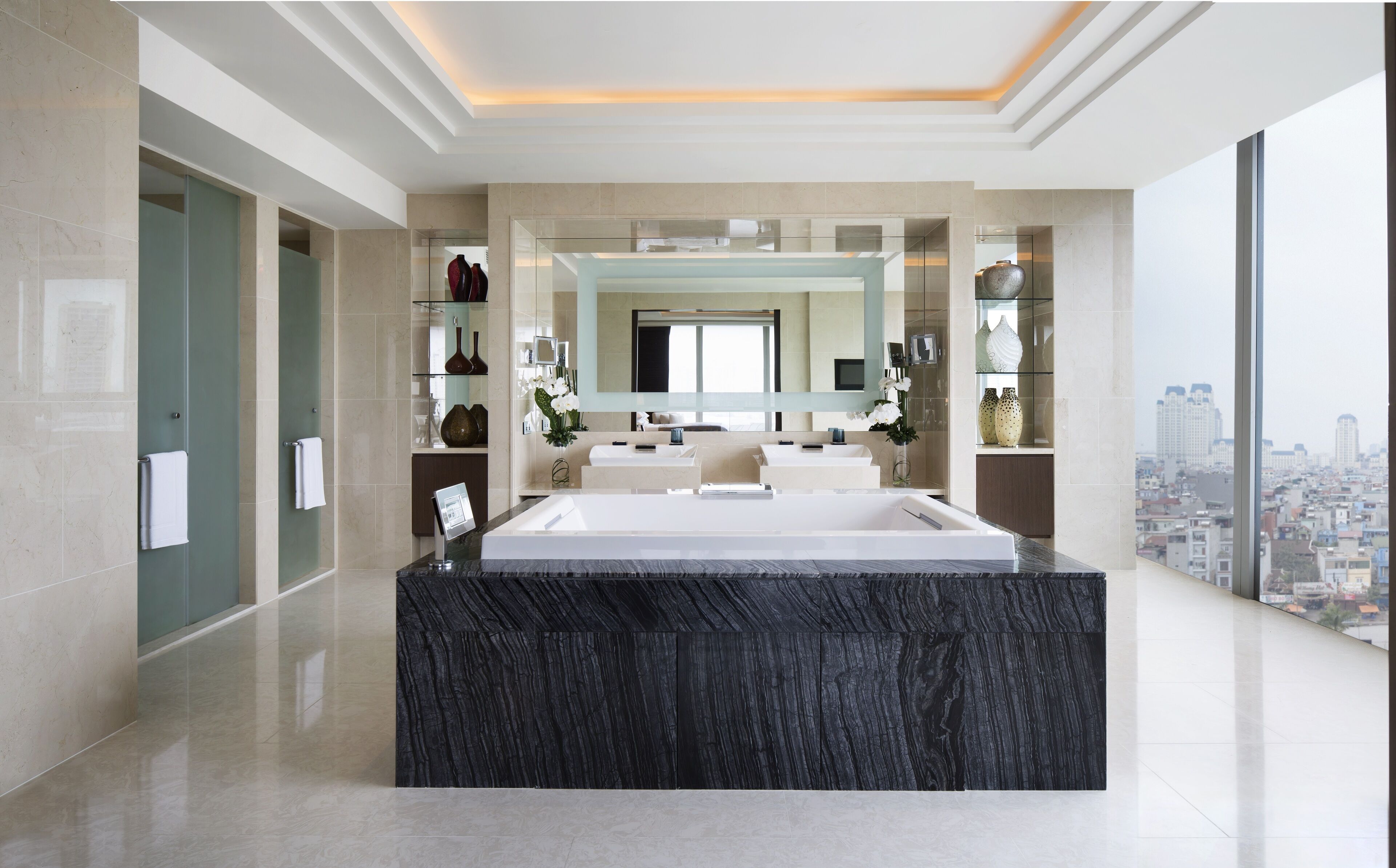 Un bagno moderno con un ampio lavabo in marmo, una cabina doccia in vetro e vista sulla città.