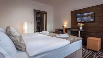 A hotel room with a bed, a desk, a TV, and a view of a lake.