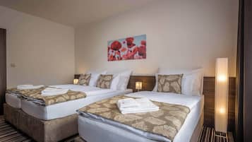 A hotel room with two beds, each with a patterned bedspread and pillows, a wall-mounted artwork, and a bedside lamp.