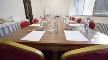 A conference room with a long table, red chairs, water bottles, and documents.