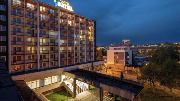 Un hôtel à plusieurs étages, reconnaissable à son enseigne bien visible où l’on peut lire « HÔTEL SATEL ».