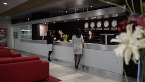 Un espace d’accueil avec un comptoir, une horloge et un canapé rouge.